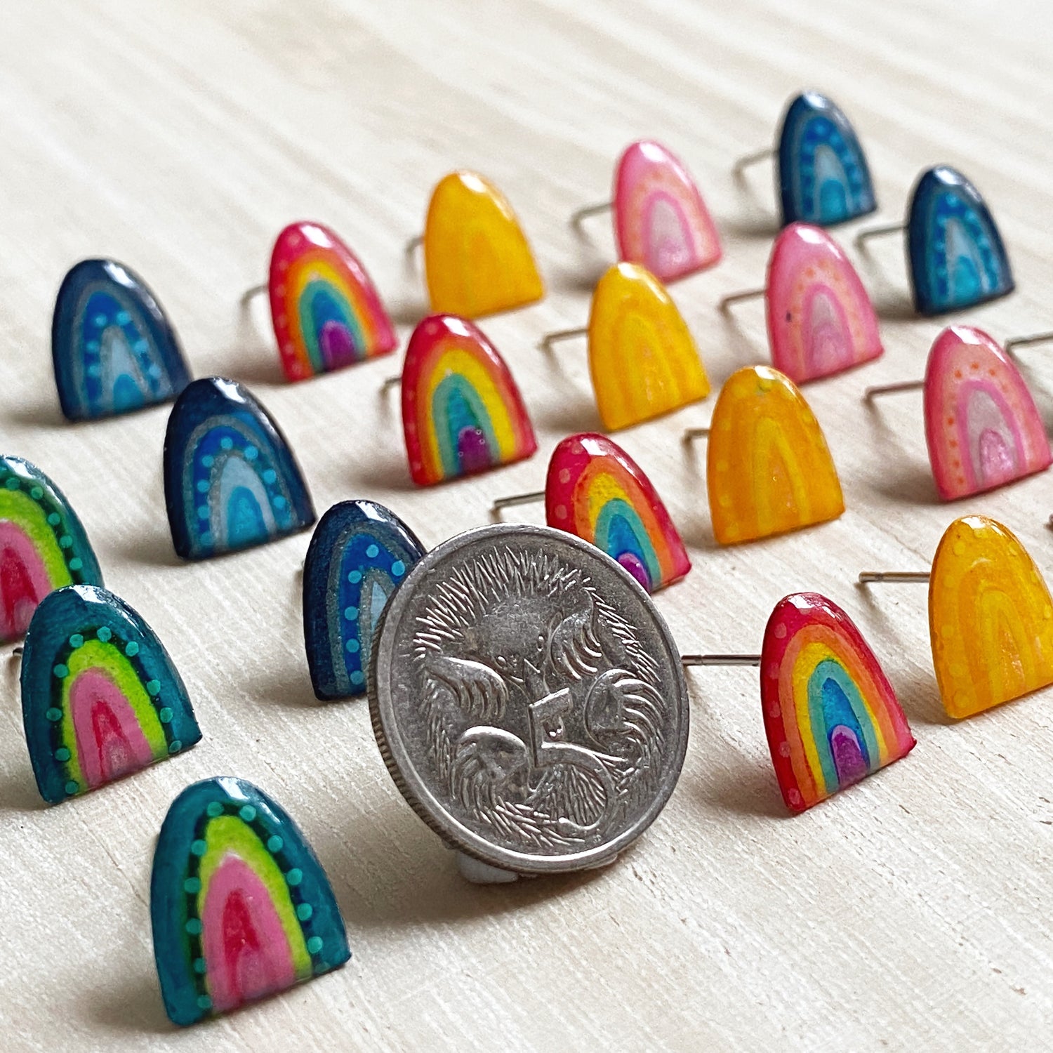 mini rainbow stud earrings next to a 5 cent coin
