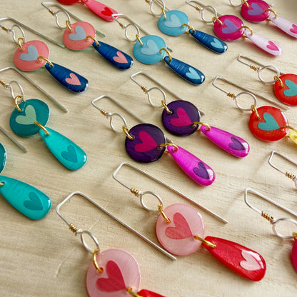 Colorful heart-shaped earrings on a light wooden surface