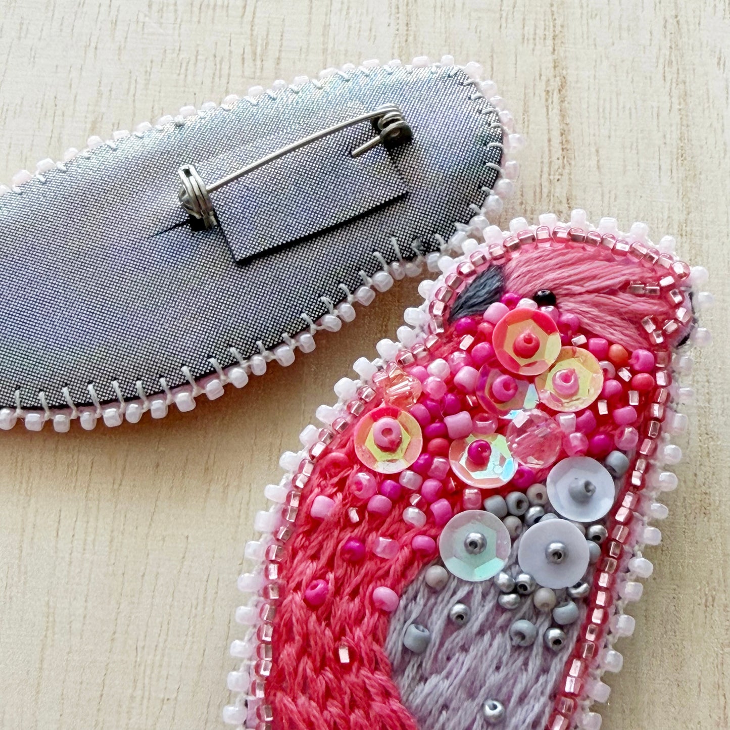 Decorative brooch with pink and gray design on a light wooden surface