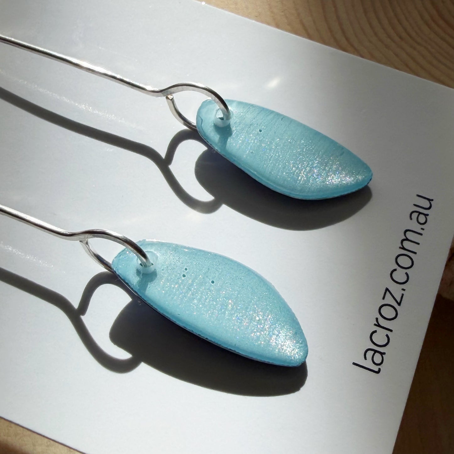 closeup of light blue organic teardrop earrings on business card