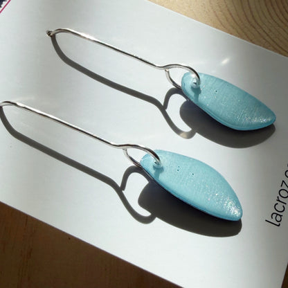 closeup of light blue organic teardrop earrings on business card
